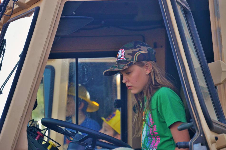 A girl learns about the cab of a U.S. Army rig.