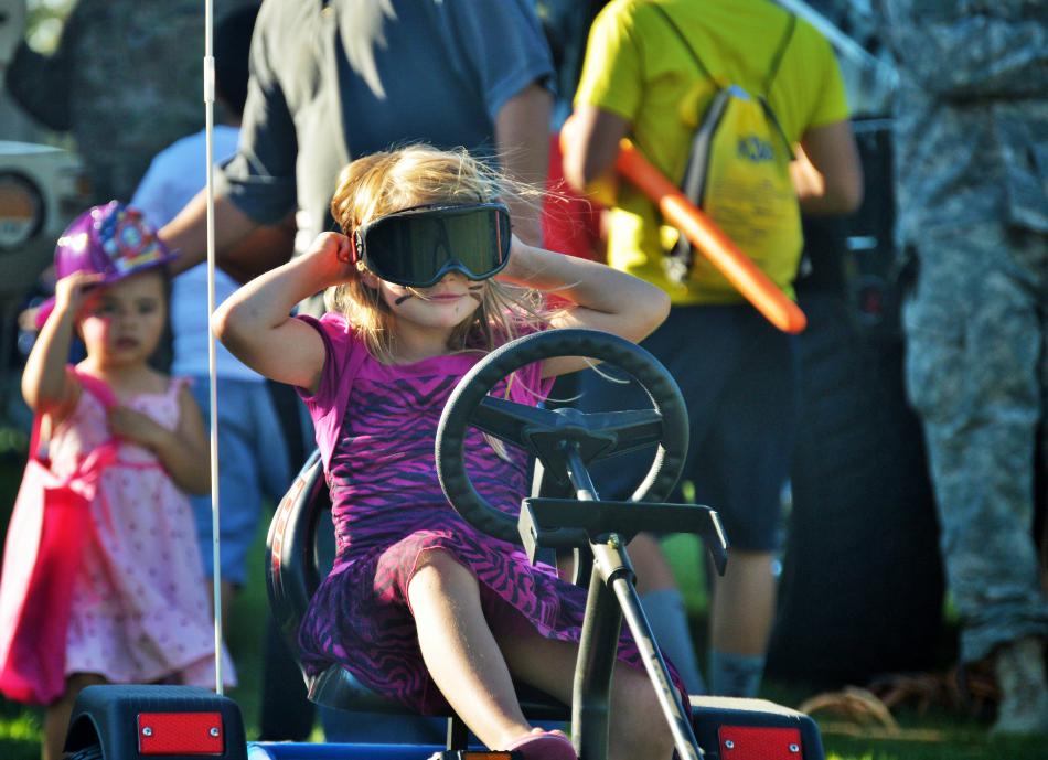 A girl fastens eye gear in preparation for her go-kart ride.