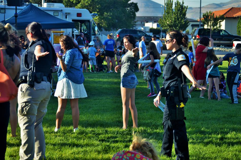 Police officers and visitors dance to the hokey pokey.
