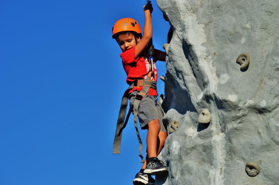 A boy ascends the rock climbing wall.