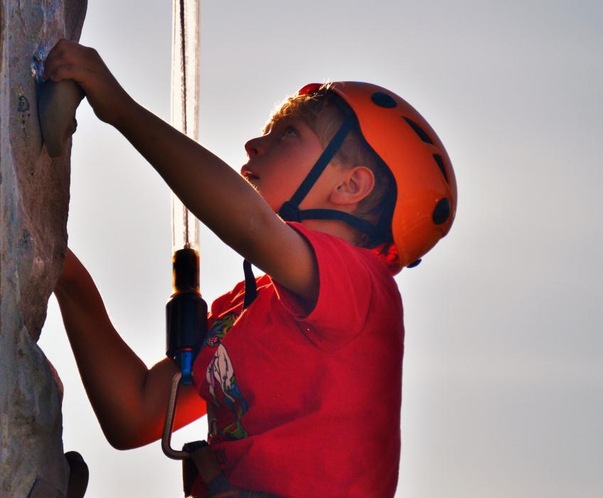 A boy works his way up the rock climbing wall.