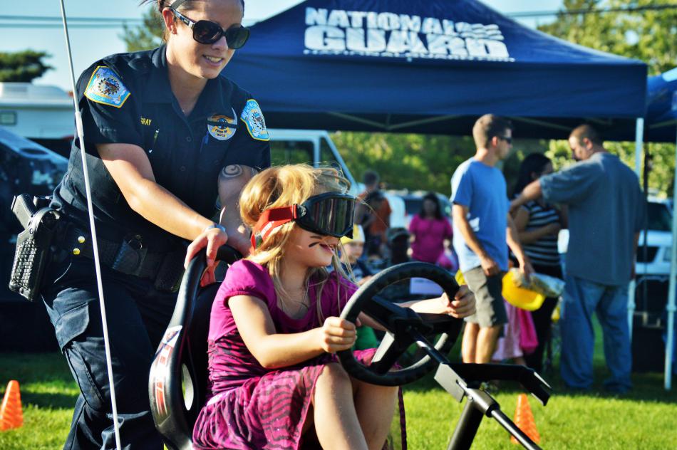 An NHP officer pushes a girl in a go-kart.