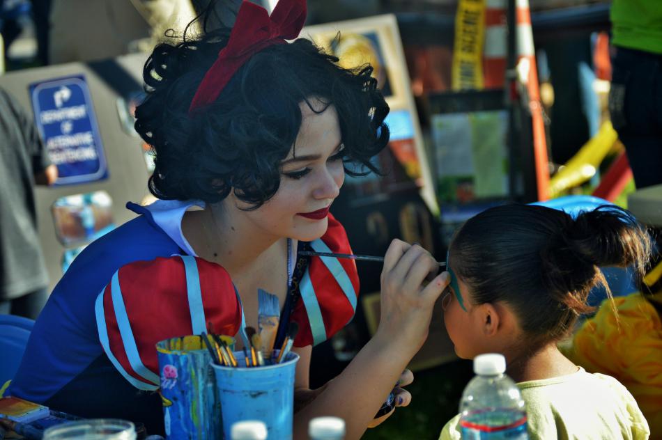 Snow White paints the face of a young girl.