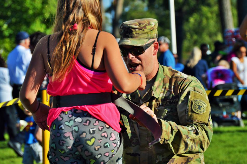 A U.S. Army soldier fastens a rock climbing harness to a child.