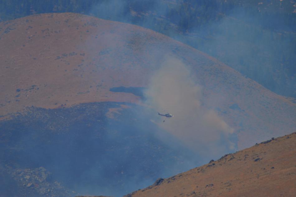 Photo by Lisa Fisher. A chopper drops water on the fire behind C Hill Sunday.