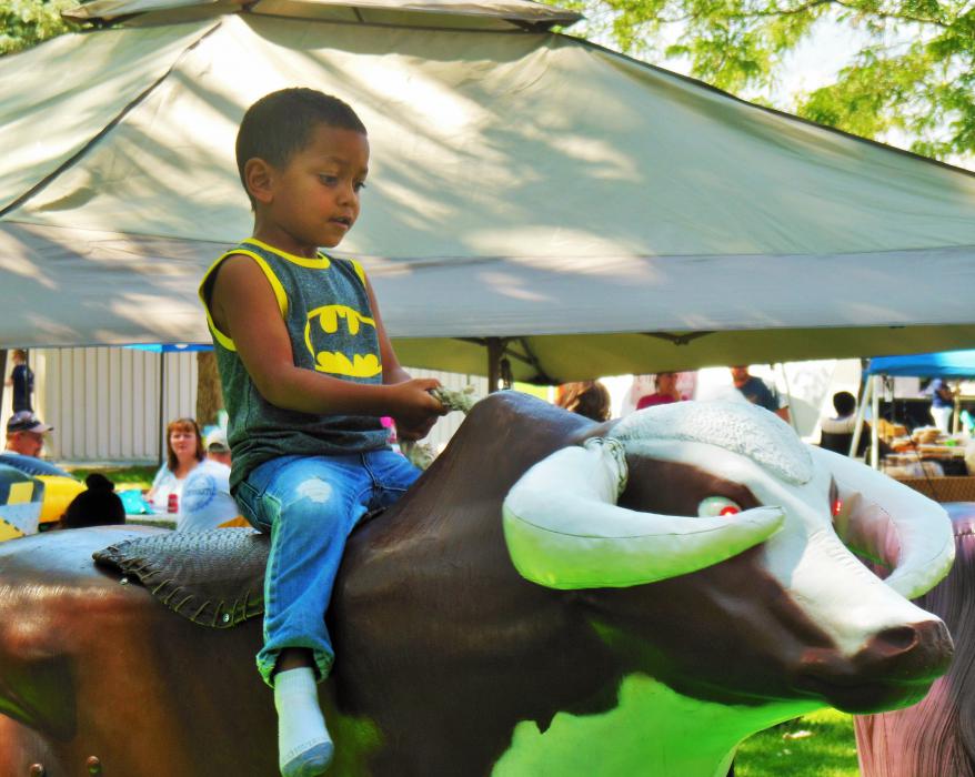 A boy rides a mechanical bull Saturday at Mills Park.