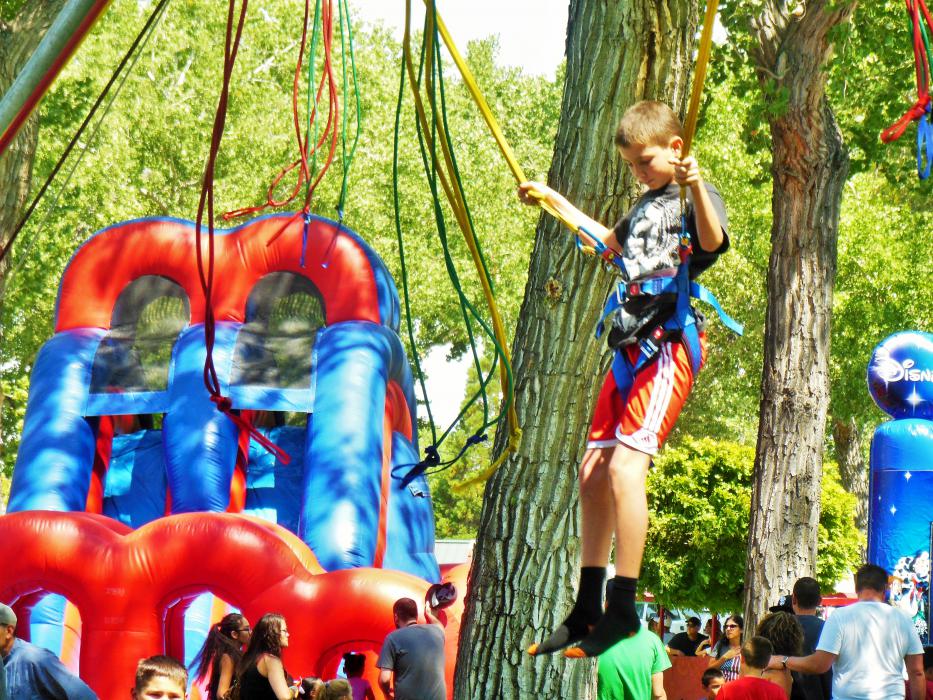 A boy gleefully bounces from the bungee lines.