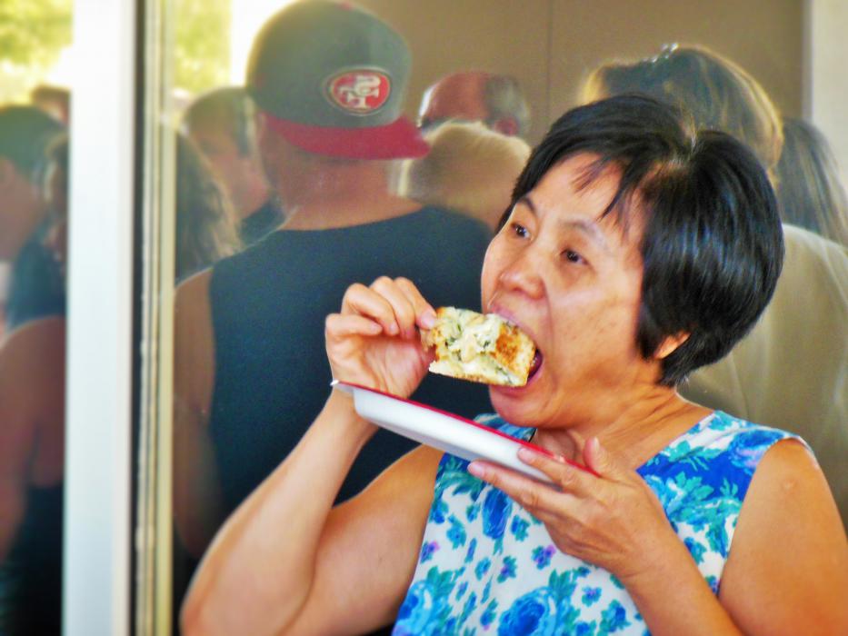 A woman bites into a slice of chicken alfredo pizza Wednesday at Papa John's.