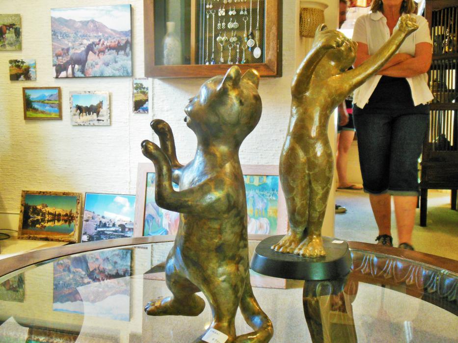 Whimsical feline figurines displayed on a table inside the main art gallery room.