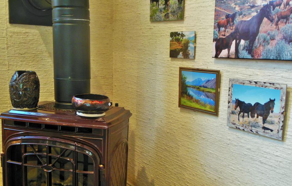 Corner wood stove dressed with pottery art and wild horse photography along the wall.