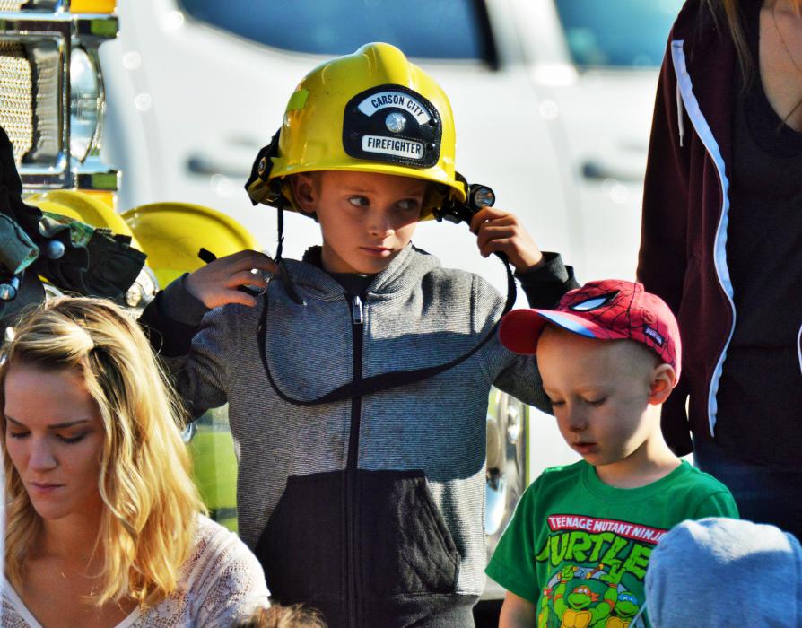 A boy wears his dad's firefighter helmet.