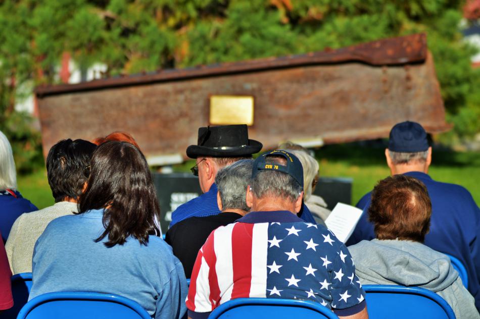 Visitors seated in front of the 9/11 I-beam memorial at Mills Park.