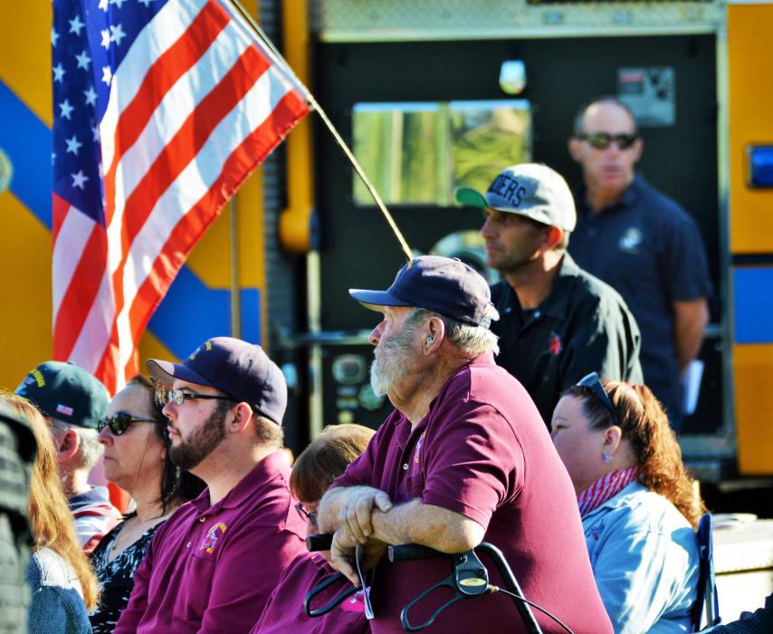 Military service veterans with an American flag in the background.