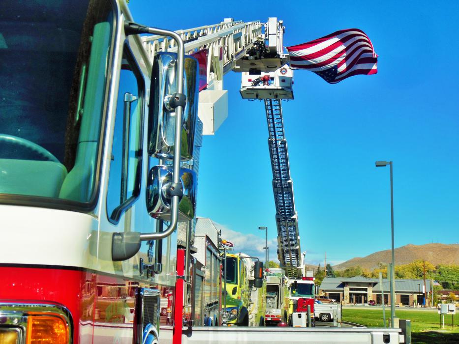 Trucks display the American flag from atop their hoisted ladders.