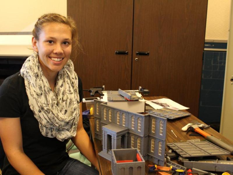Mikaela Bigley is assembling the pieces of the 3D replica of the Carson City Mint that will adorn the commemorative cake.