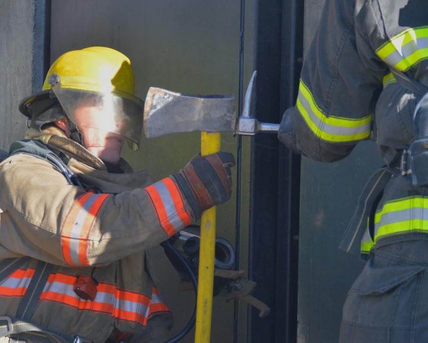 Firefighters work to force open a door to a burning building.