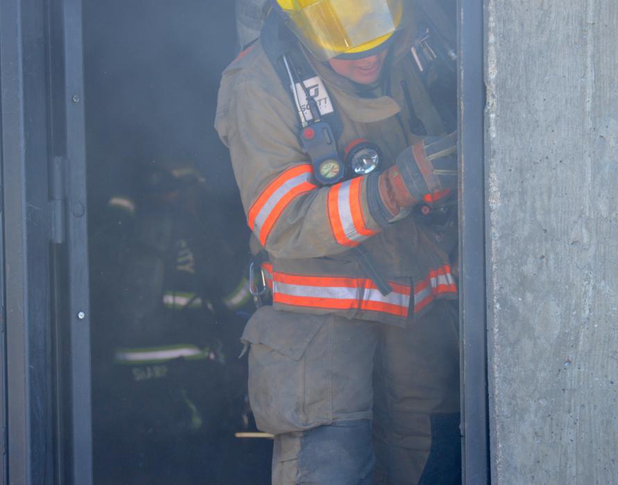 Firefighters work through thick smoke inside a burning building.
