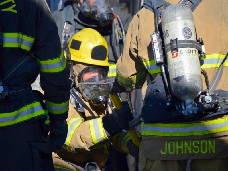 Photos by Brett Fisher. A firefighter uses the blunt end of an axe as a hammer to force open a door.