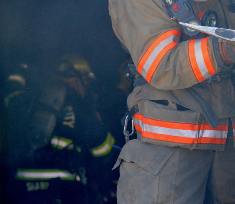 Firefighters work their way through heavy smoke inside a dark building.
