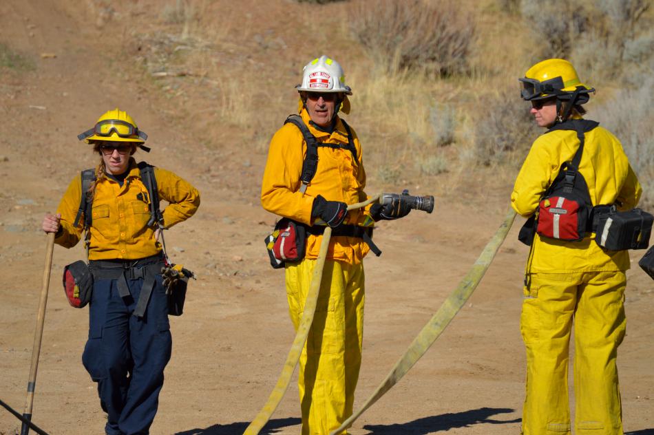 Wildland firefighters stretch out hoses from an engine along Goni Canyone Rd.