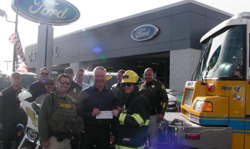 Capital Ford General Manager Tim Milligan presents a $2,500 check to the Holiday with a Hero campaign.