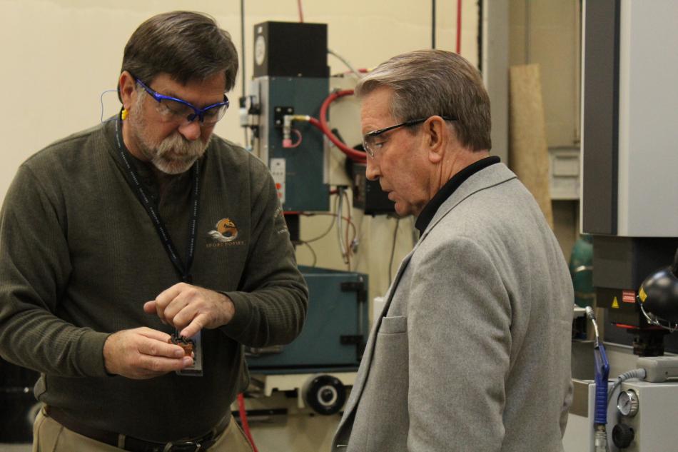 Ralph Strahan, director of engineering for Click Bond, and Carson City Mayor Bob Crowell examine machine parts.