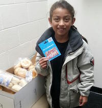 Angel opening his NHS food basket and holding his gift card.