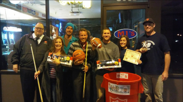 Captain Mark Cyr collecting toys with the bartender and patrons of MJ's
