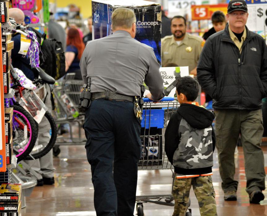 A law enforcement officer and boy go shopping inside Wal-Mart.