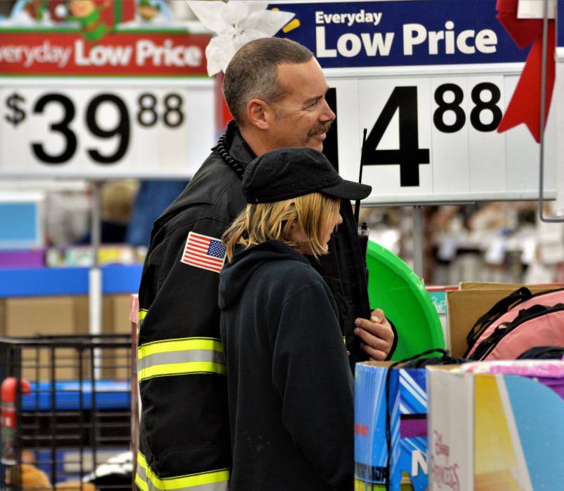 A firefighter and boy pose for photos while shopping inside Wal-Mart.