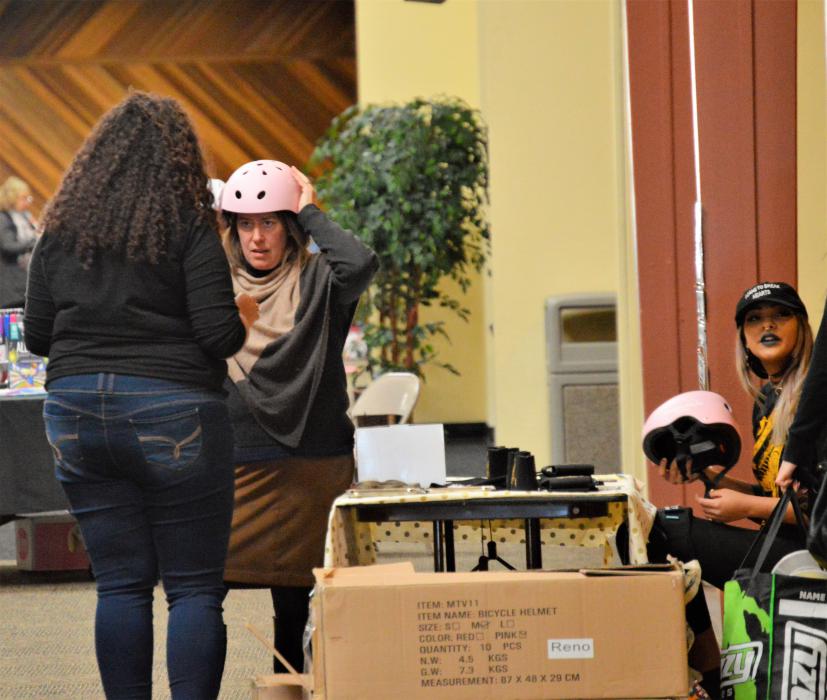 Photo by Brett Fisher. Carson Victory Rollers help fit free helmets to visitors.