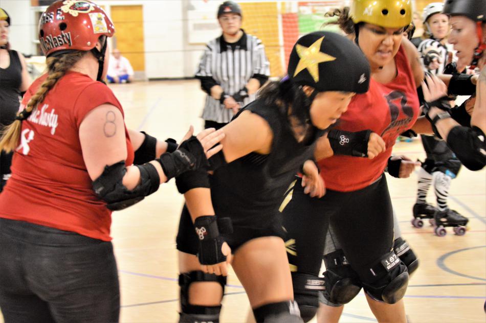 One skater checks another to stop momentum and prevent a score.
