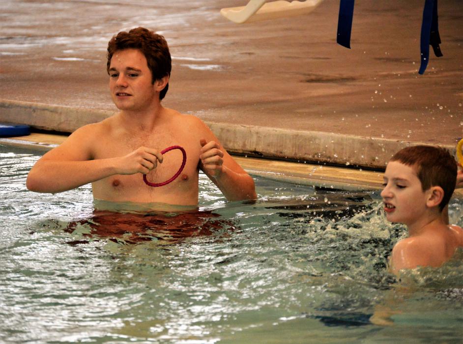 Sam Chenin (right) and instructor Miles Bean toss rings toward the center of the pool.
