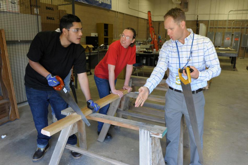 WNC instructor Nigel Harrison provides a lesson in using a saw to Susanne Whimple and Cristian Avila.