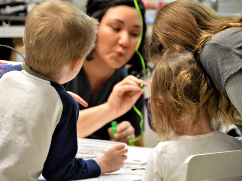 Photos by Brett Fisher. Dr. Teresa Brandstetter sits with children Saturday at a coloring station.