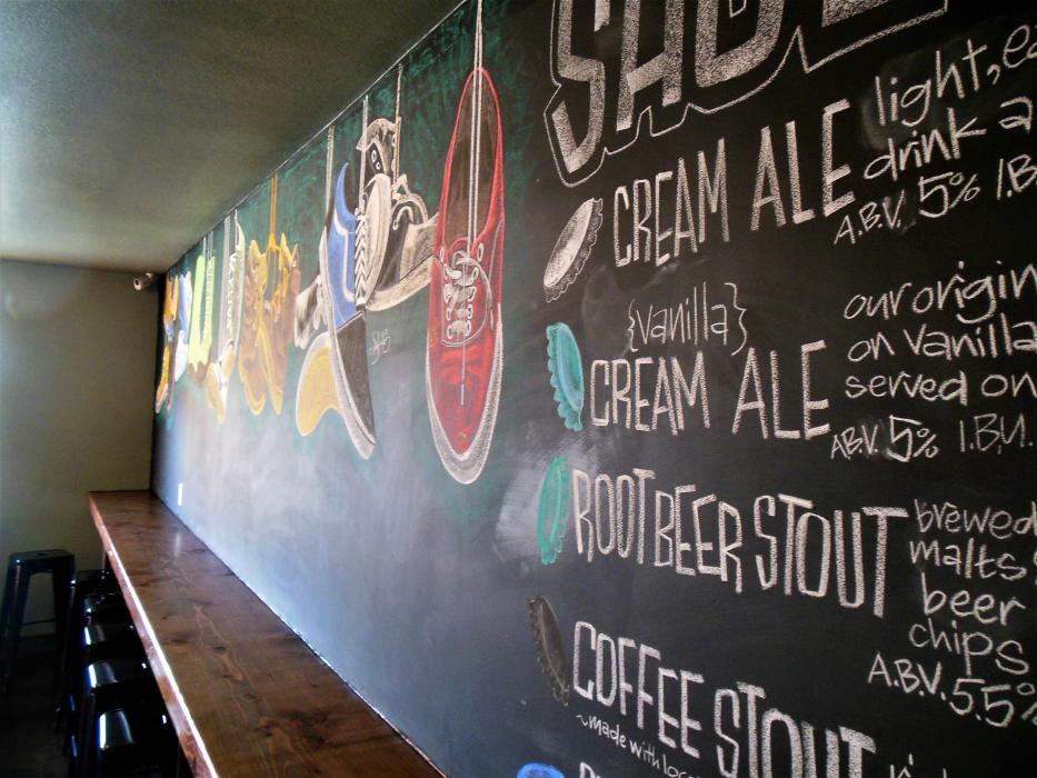 Art wall and menu inside the tasting room at the Shoe Tree Brewing Company.