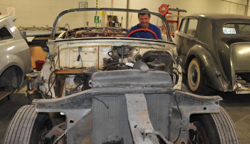 Jason Spohr, an auto mechanics instructor, sits behind the wheel of a 1953 Cadillac that will be restored in class.