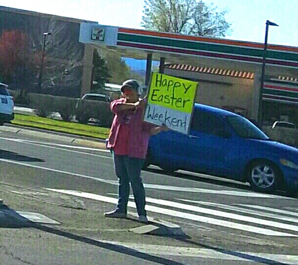 Photo by Brett Fisher. E.D. Crouser wishes motorists Happy Easter Friday during afternoon rush hour.