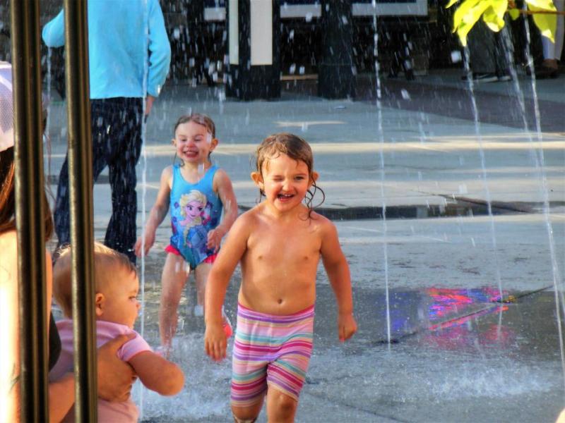 Photos by Brett Fisher. Children run through the water fountain on McFadden Plaza Saturday.