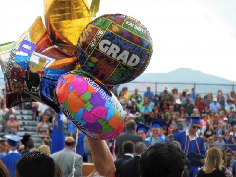 Graduation balloons in the foreground of CHS seniors receiving their diplomas.