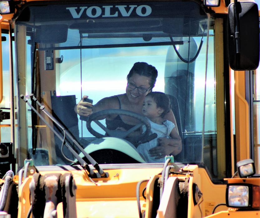 A mom and child sit in the cab of a bulldozer Saturday.