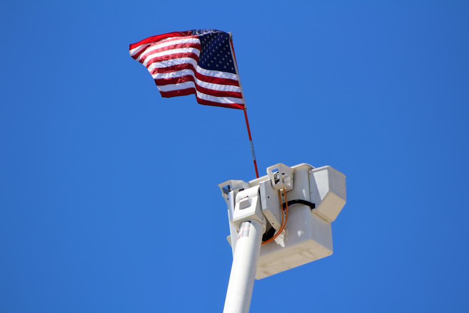 An American flag flies from the utility bucket of a snorkel device attached to a truck.