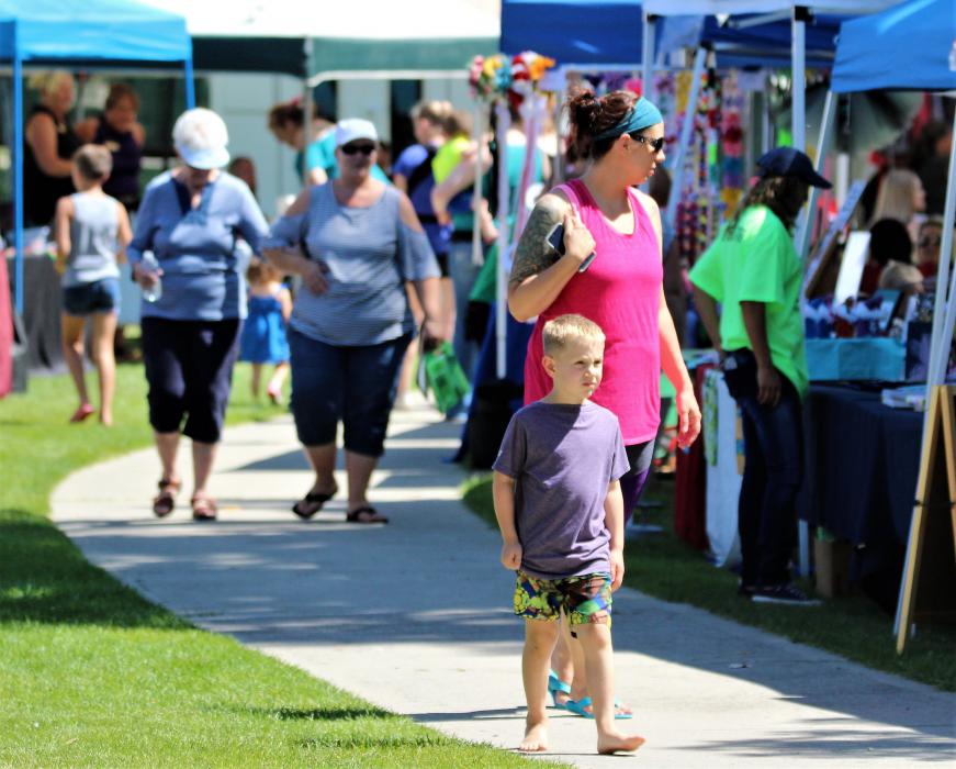 A mother and her son stroll through the vendor booths in Mills Park.