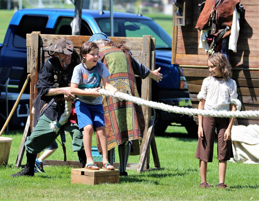A pirate and a youth work together in a game of tug of war Saturday.