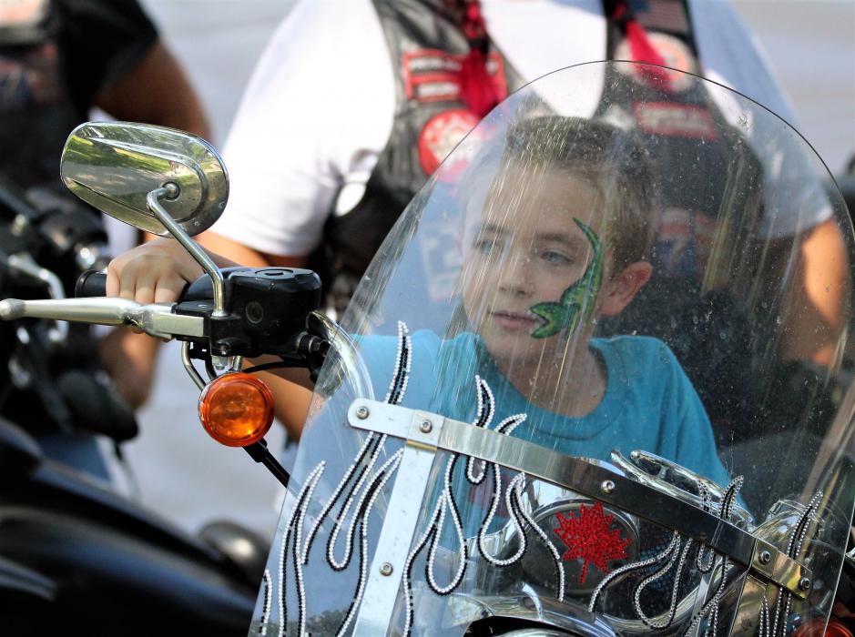 A boy sits on a motorcycle from the Bikers Against Child Abuse club Saturday in Mills Park.