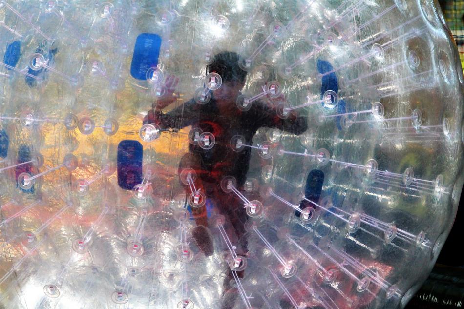 A youth from inside a hamster ball Saturday in Mills Park.