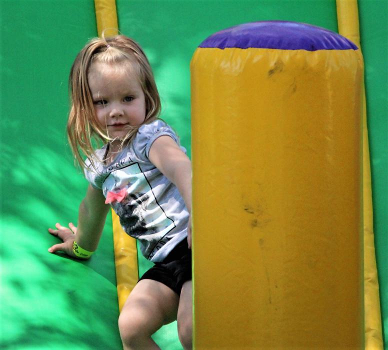 A little girl reaches the bottom of an inflatable slide Saturday in Mills Park.
