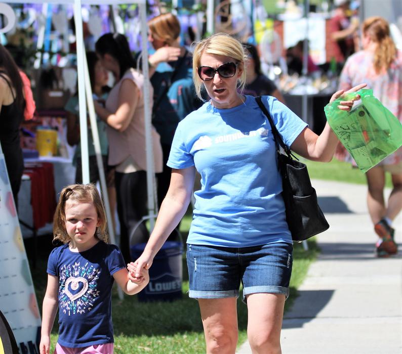 A mother and daughter walk by vendor booths in Mills Park Saturday.