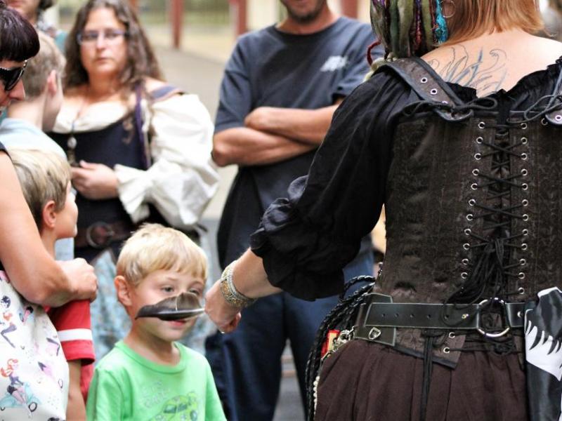 Photos by Brett Fisher. A lady pirate tickles a child with a feather Saturday.
