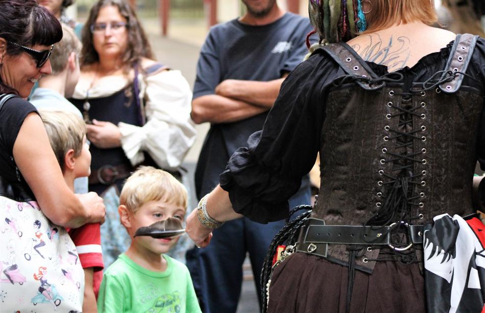 Photos by Brett Fisher. A lady pirate tickles a child with a feather Saturday.